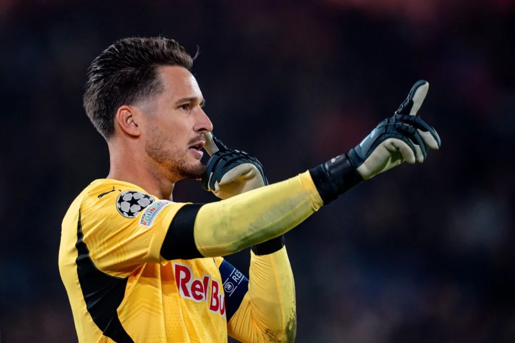 Torwart Janis Blaswich vom RB Salzburg hebt die rechte Hand und gestikuliert auf dem Fußballfeld