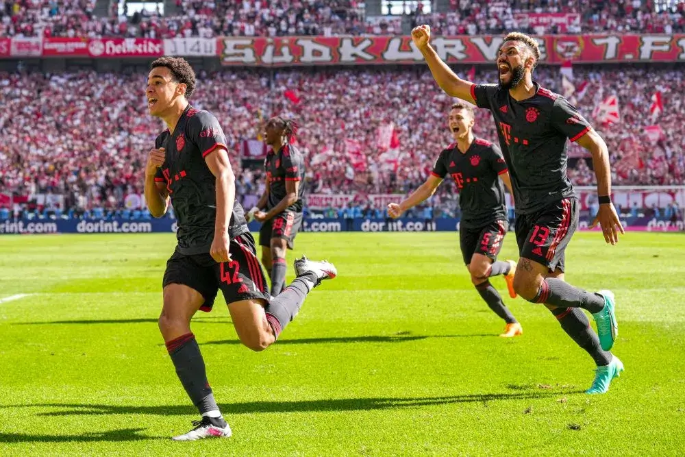 Jamal Musiala läuft über das Fußballfeld und bejubelt mit Mitspielern sein Tor