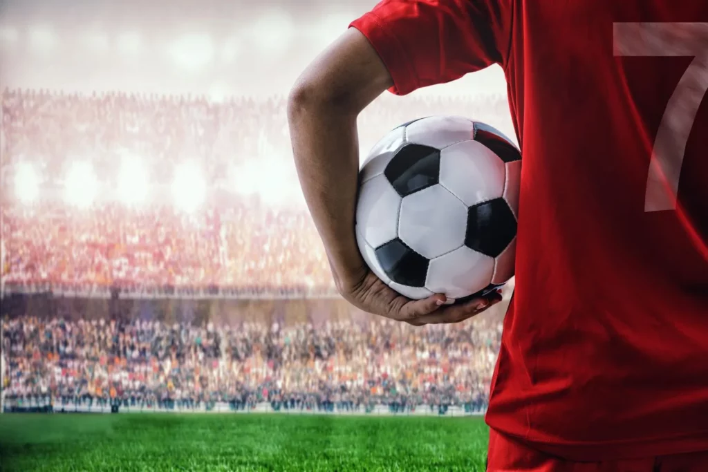 Mann hält Fußball unter dem Arm und blickt auf die Ränge im Fußballstadion